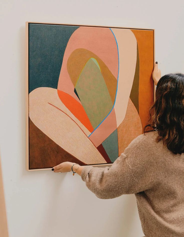 a woman is painting on the wall in an art gallery