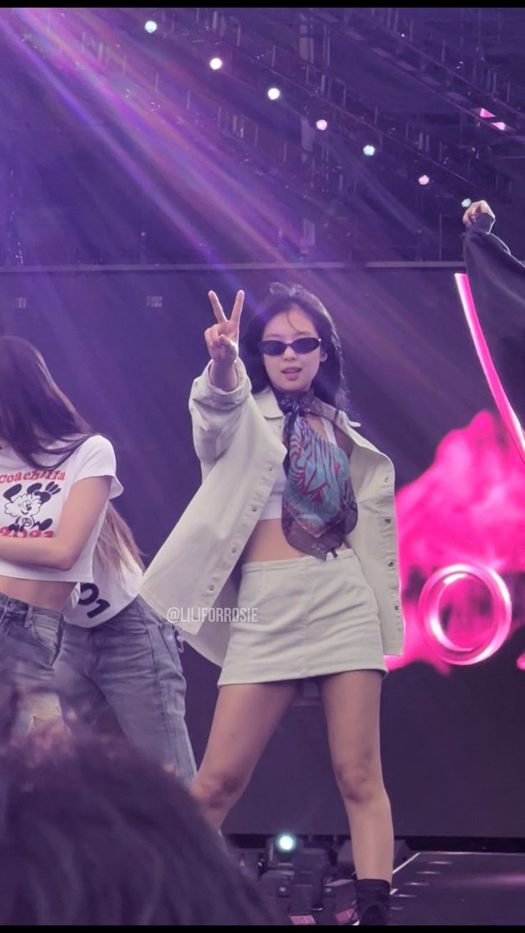 two young women are performing on stage with one holding up the peace sign and the other standing behind her