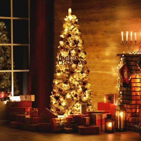 a decorated christmas tree in front of a fireplace with lit candles and presents under it