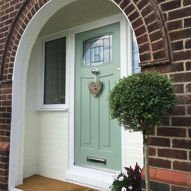 a green door with a heart decoration on it's front entrance to a brick building