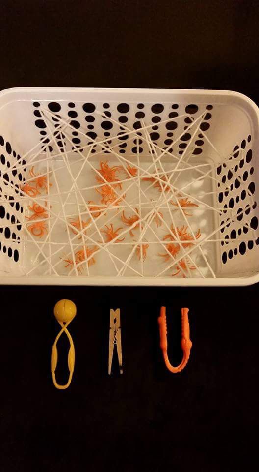 some scissors are sitting in a white basket with orange string attached to the handles and hooks