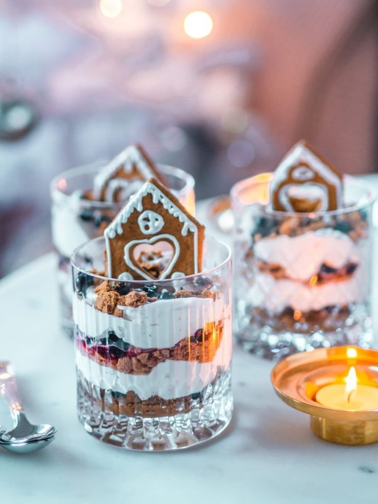 small gingerbread houses in glass cups on a table next to a tea light candle