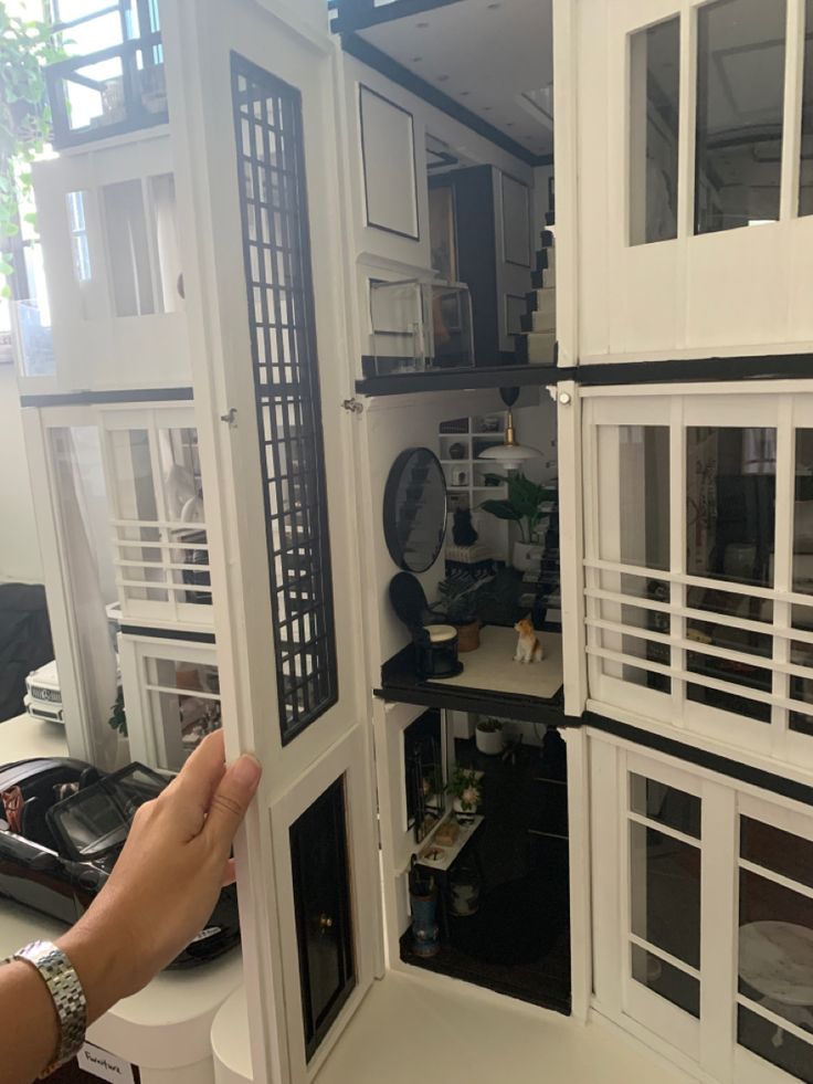 someone is holding up the inside of a doll house with all its windows and doors open