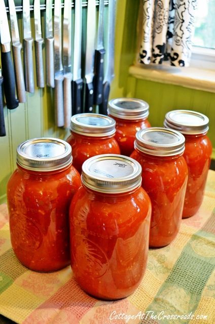 six jars of tomato sauce sitting on a table with utensils in the background