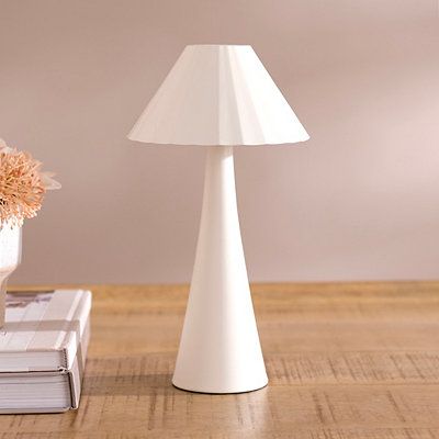 a white lamp sitting on top of a wooden table next to a vase with flowers