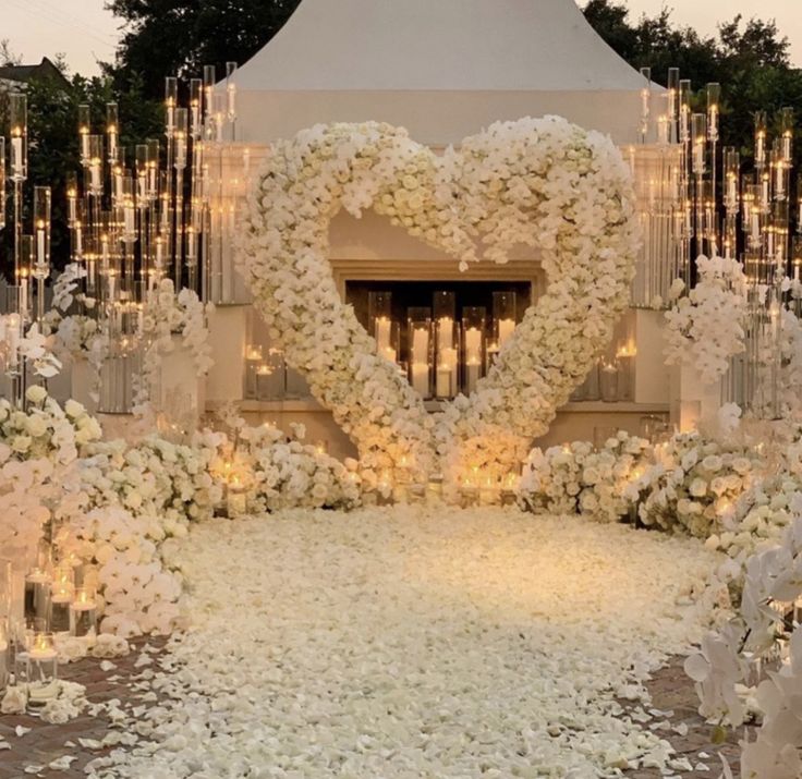 a heart - shaped arrangement is surrounded by candles and flowers