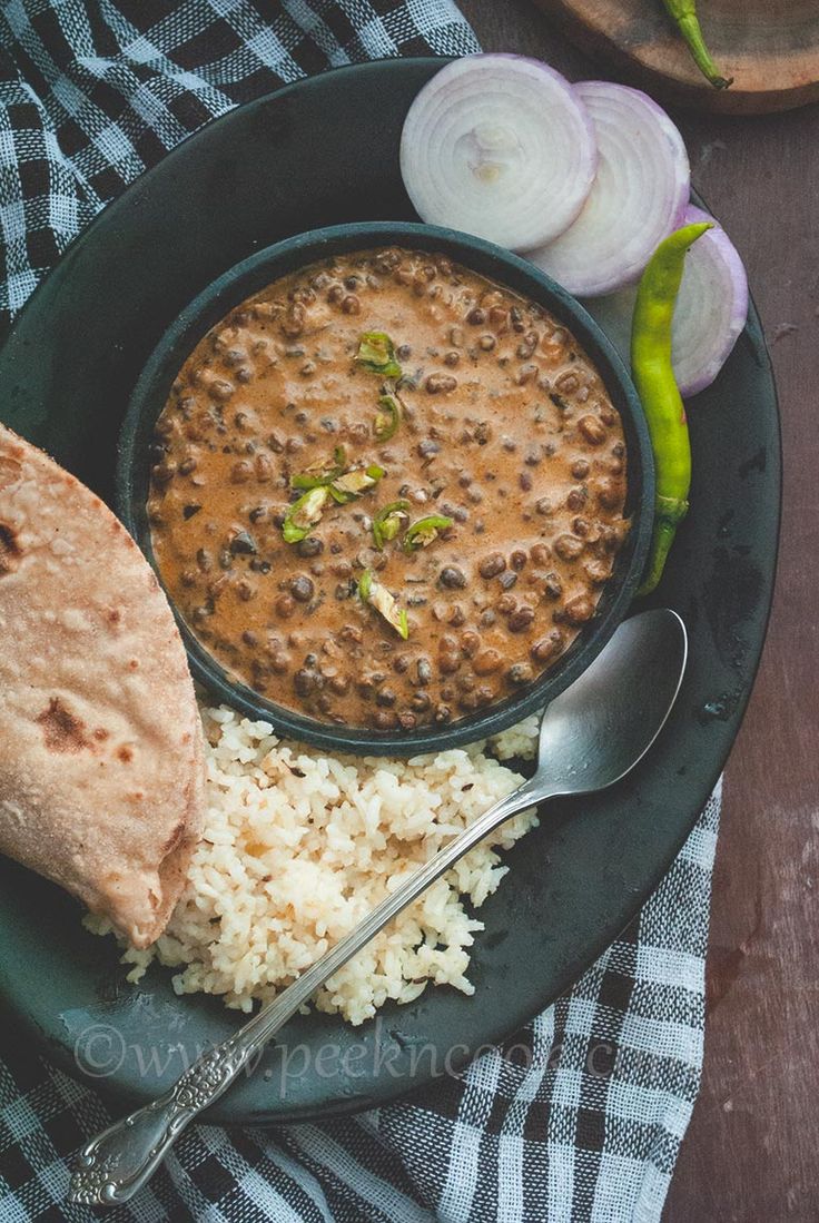 a plate with rice, beans and pita bread next to some onion wedges