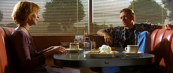 two people sitting at a table with plates of food and cups in front of them