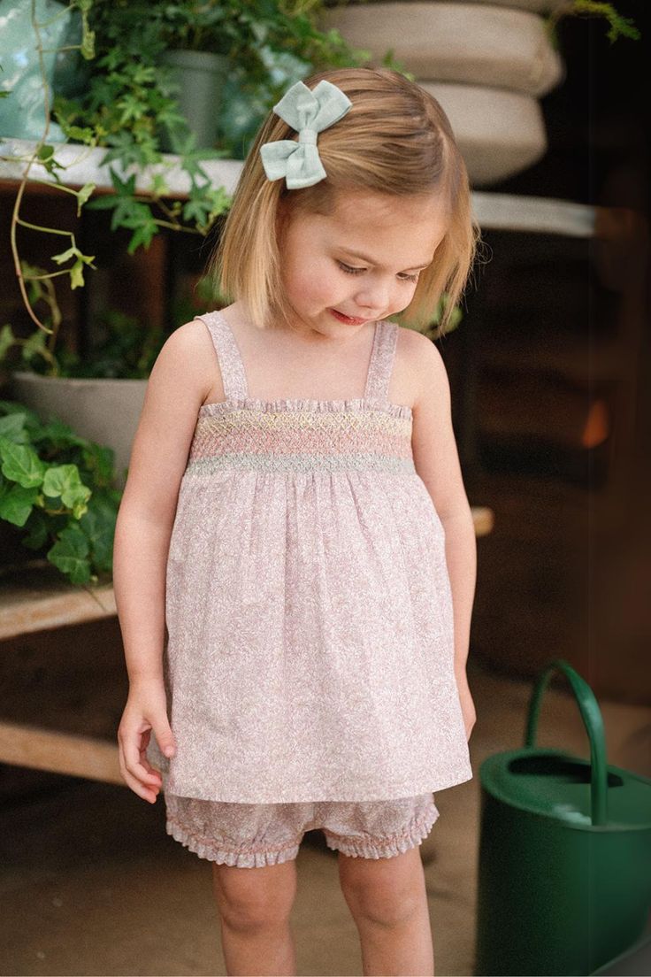 Our two-piece Rosie Baby Set in our new Scattered Blooms print is functionality garbed in sweet femininity. The swing style top features a darling, hand-smocked rainbow threaded across dainty petals of rosy pink daylilies and tiny daisies. On the bottom, our best-selling Lulu Bloomer frees up those squirmy legs to move Playful Floral Smocked Dress For Summer, Playful Smocked Floral Dress For Summer, Playful Smocked Dress With Floral Print For Summer, Playful Summer Smocked Dress With Floral Print, Playful Pink Smocked Dress, Cute Pink Smocked Dress With Smocked Back, Pink Smocked Dress For Summer Playtime, Pink Smocked Dress For Playtime In Summer, Playful Smocked Dress For Spring With Smocked Bodice