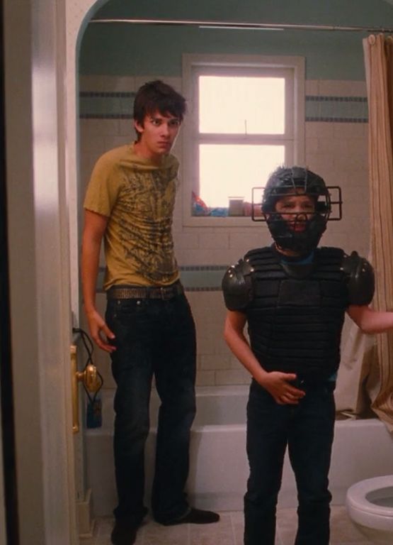 two young men standing in a bathroom next to a toilet