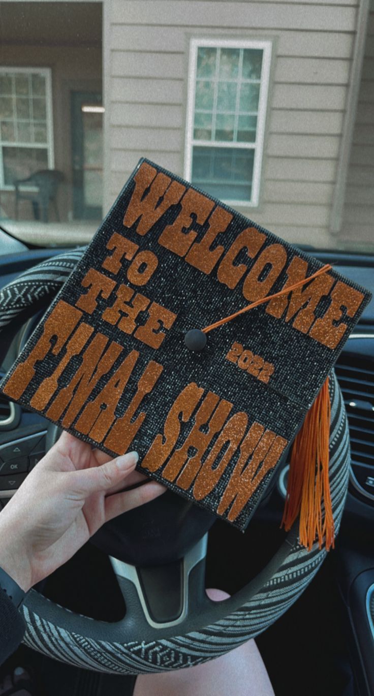 a person in a car holding up a graduation cap with the words wrong side of the road on it