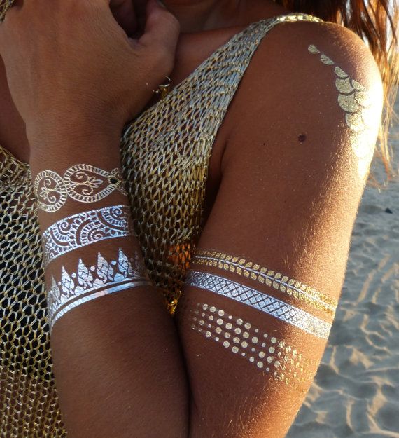 a woman with gold and white tattoos on her arm