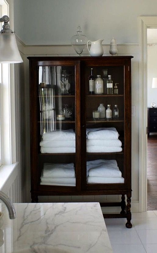 a cabinet with towels and other items on it in a room that has white tile flooring