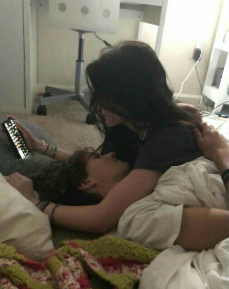 a woman laying in bed next to a man with a remote control on his chest