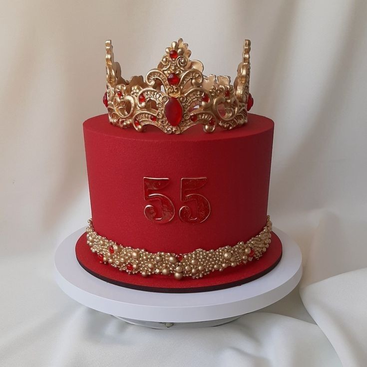 a red cake with gold decorations and a crown on top