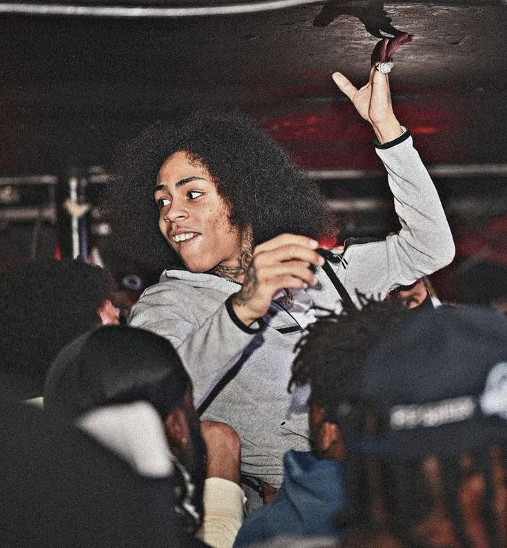 a man with an afro holding up a bird in the air above his head while standing next to other people