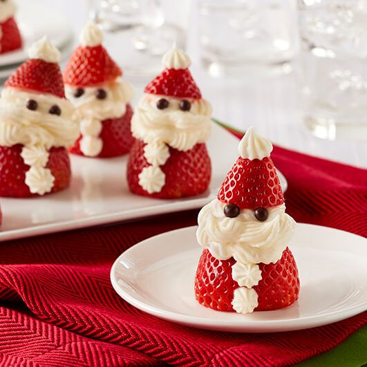 some strawberries with santa clause on them are sitting on a plate next to other small ones