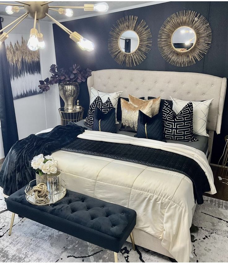 a bedroom with black and white decor on the walls, gold mirrors above the bed