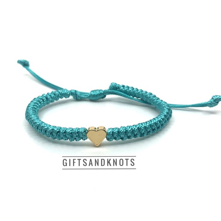 a blue string bracelet with a gold heart charm on it and the words giftsanknots written below