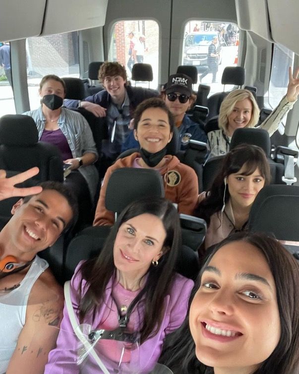 a group of people sitting in the back of a bus with their hands up and smiling