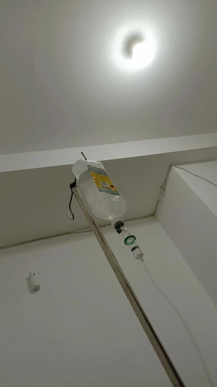 an empty bottle sitting on top of a white floor next to a ceiling light in a room