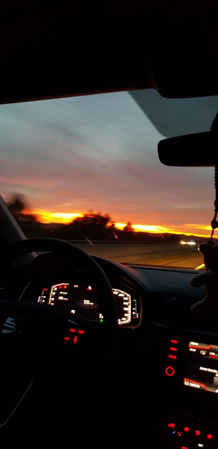 the sun is setting in the distance as seen from inside a car's dashboard