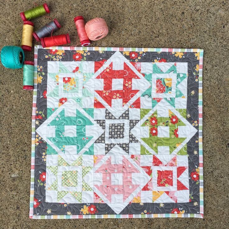 a quilt and some spools of thread on the ground