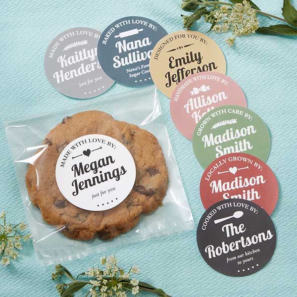 chocolate chip cookies with labels on them sitting on a blue surface next to some flowers