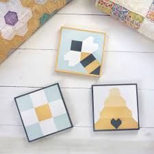 three small wooden blocks sitting next to each other on a white floor with quilts