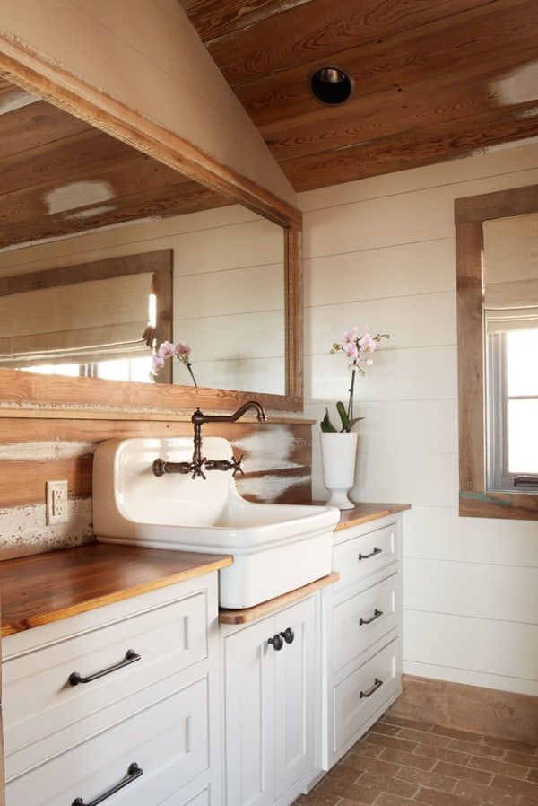 a white sink sitting under a bathroom mirror next to a wooden counter top in a room