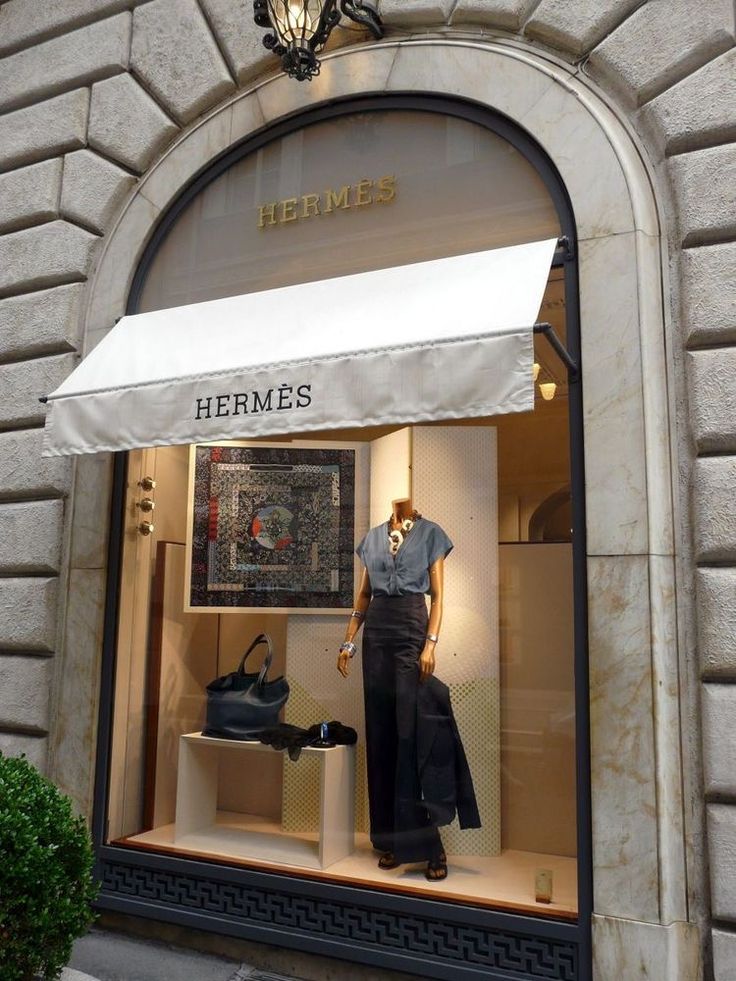 a mannequin's window display in front of a storefront with a white awning