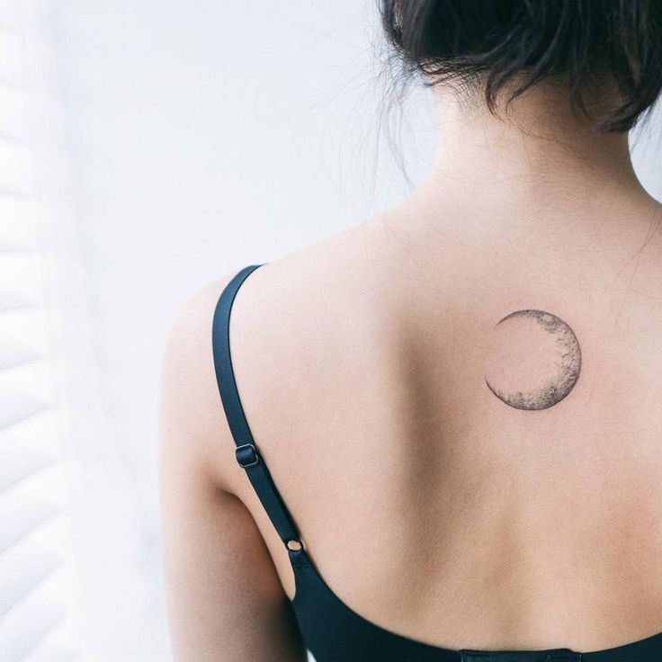 the back of a woman's shoulder with a half moon tattoo on her upper arm