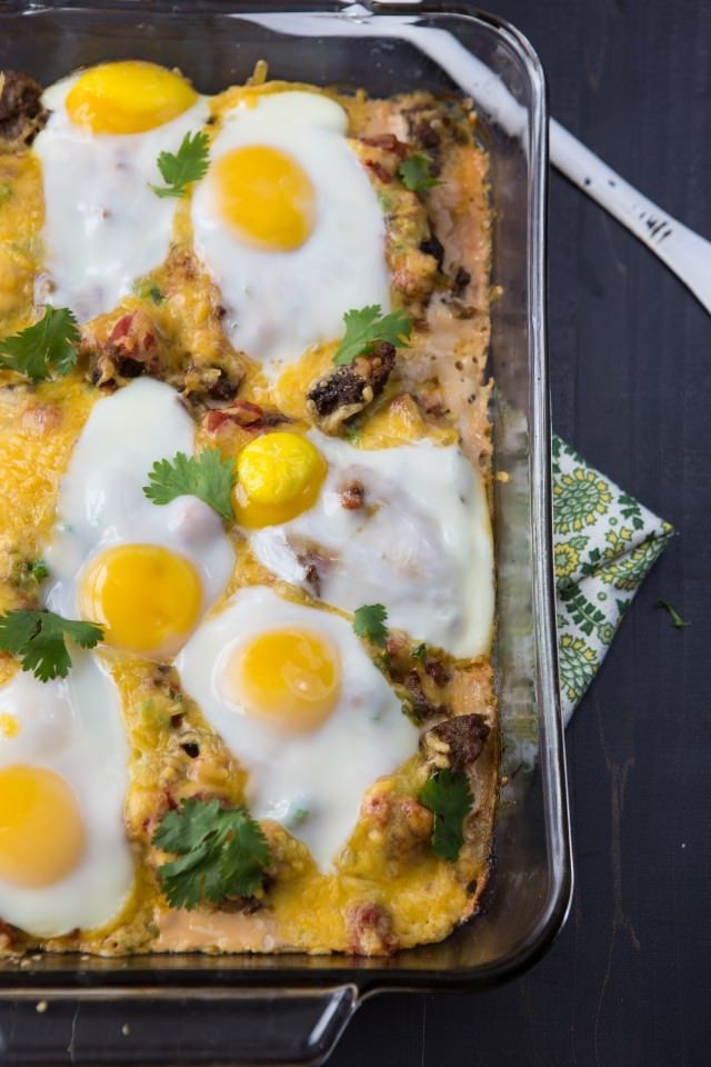 a casserole dish with eggs and meat in it, on a table next to a fork