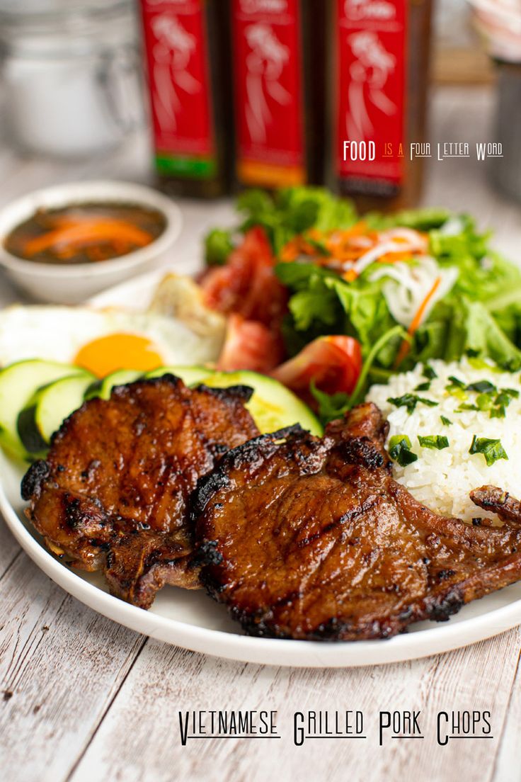 a white plate topped with meat and veggies next to bottles of ketchup