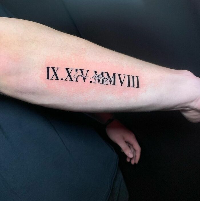 a man's arm with roman numerals tattooed on the upper half of his arm