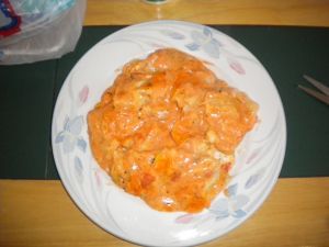 a white plate topped with pasta and cheese covered in sauce on top of a wooden table