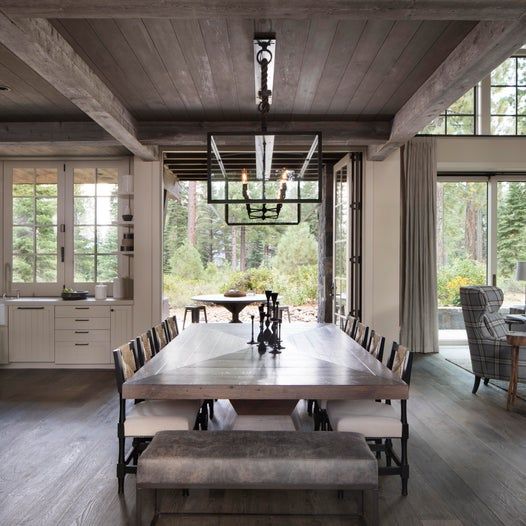 a dining room table and bench in front of large windows with lots of natural light