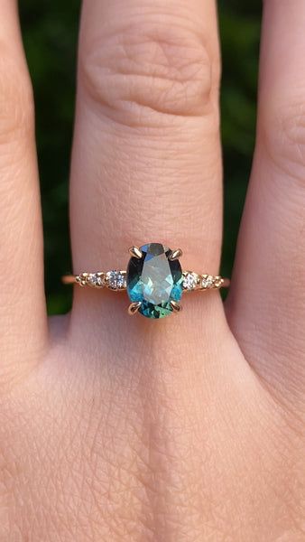 a woman's hand with a ring on it that has an oval blue and white stone in the middle