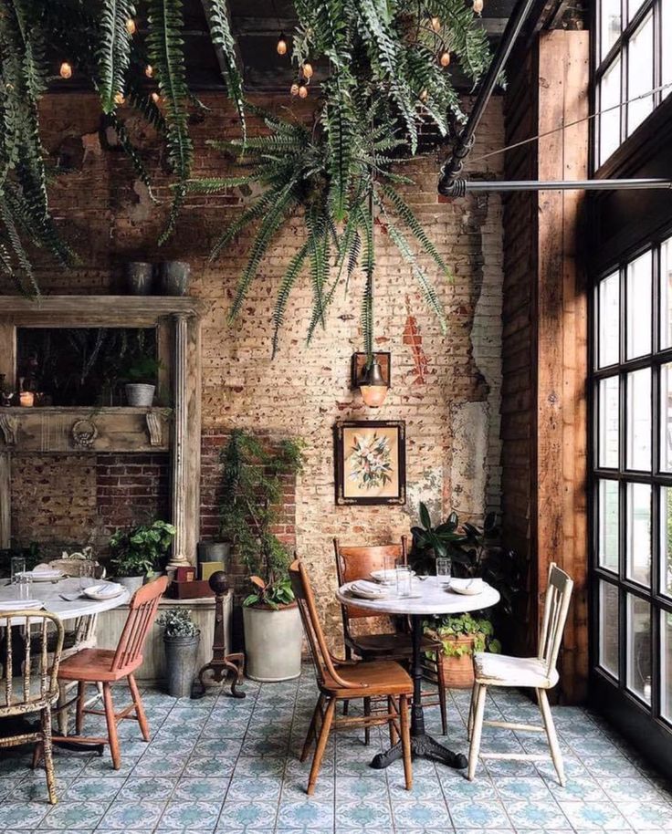 an outdoor dining area with tables, chairs and potted plants hanging from the ceiling