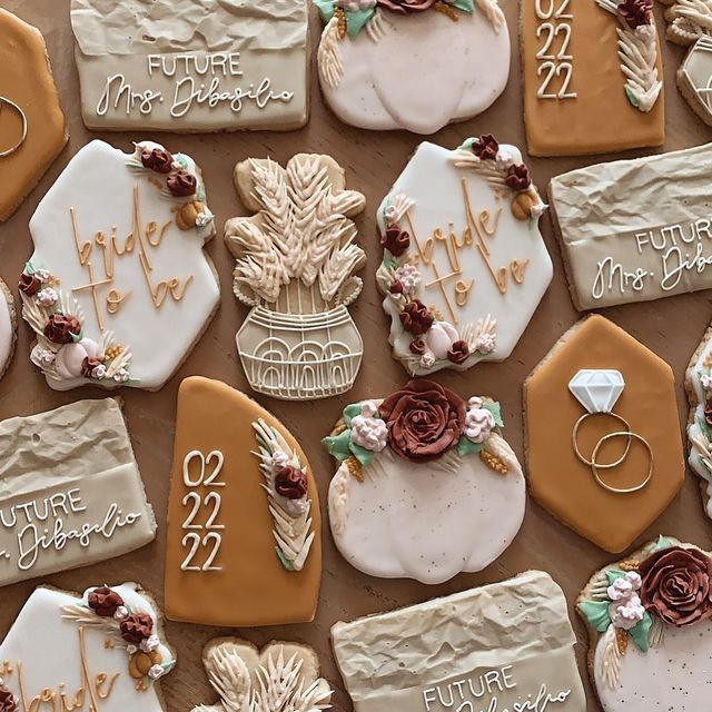 decorated cookies with names and date displayed on wooden table top, including wedding rings and flowers