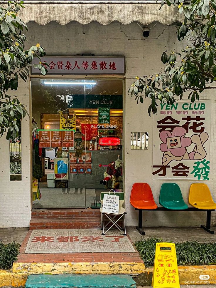 two colorful chairs sitting in front of a store with chinese writing on the walls and windows