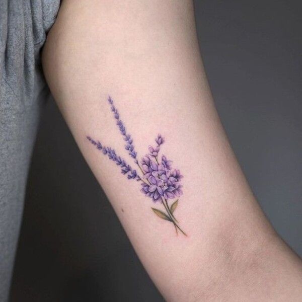 a woman's arm with purple flowers and leaves on the left side of her arm