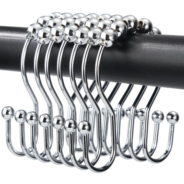 a bunch of metal balls hanging from the side of a black curtain rod on a white background