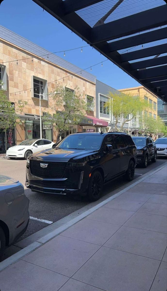 several cars parked on the street in front of a building with a awning over it