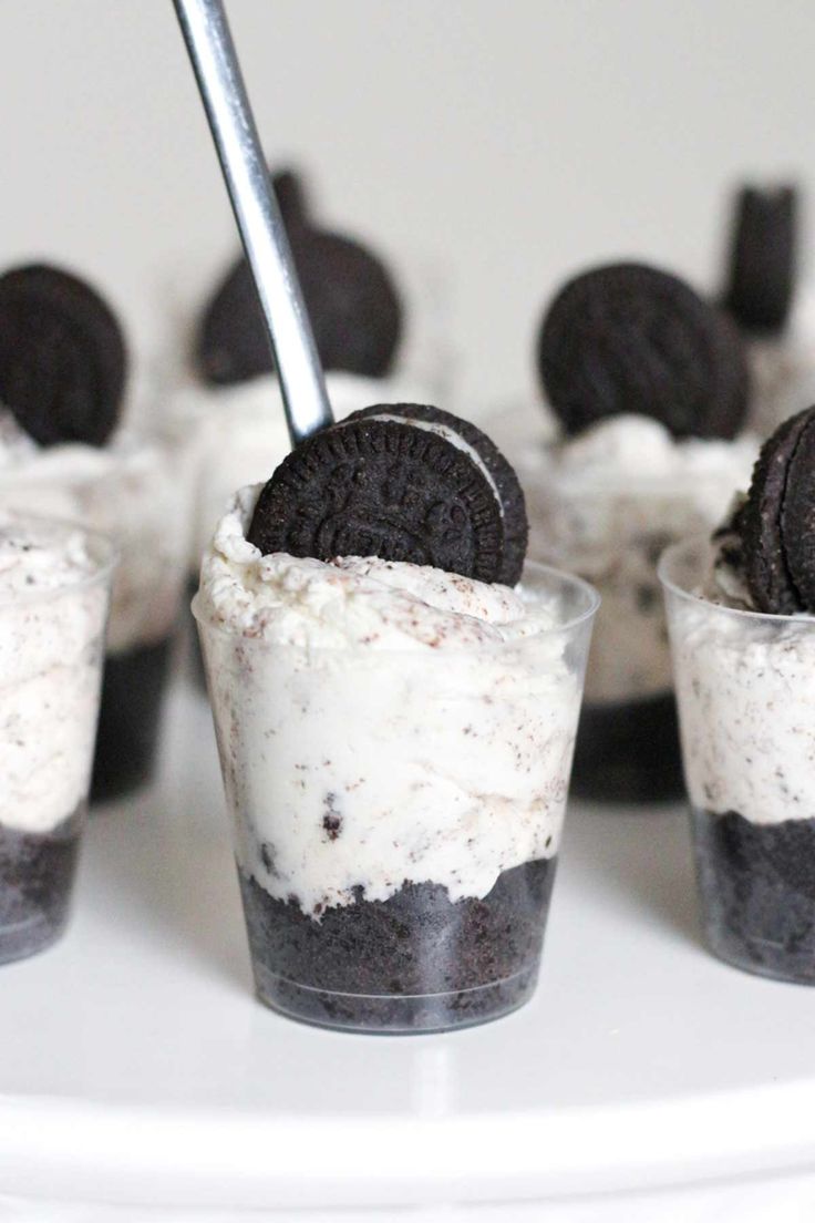 desserts with oreo cookies and cream in small cups on a white platter