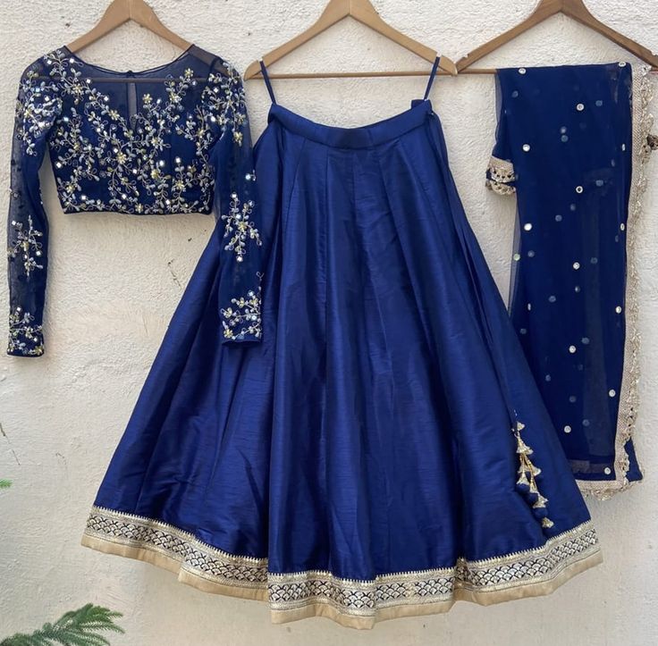 A three-piece midnight blue lehenga set from the Priti Sahni collection. This gorgeous midnight blue raw silk lehenga is paired with a Resham mirror & hand-embroidered net blouse with underlay. This outfit is completed with a midnight blue mirror work net dupatta with scalloped edging. Net Blouse, Raw Silk Lehenga, Resham Work, Work Lehenga, Net Blouses, Blue Lehenga, Embroidered Lehenga, Blue Mirror, Indian Dress