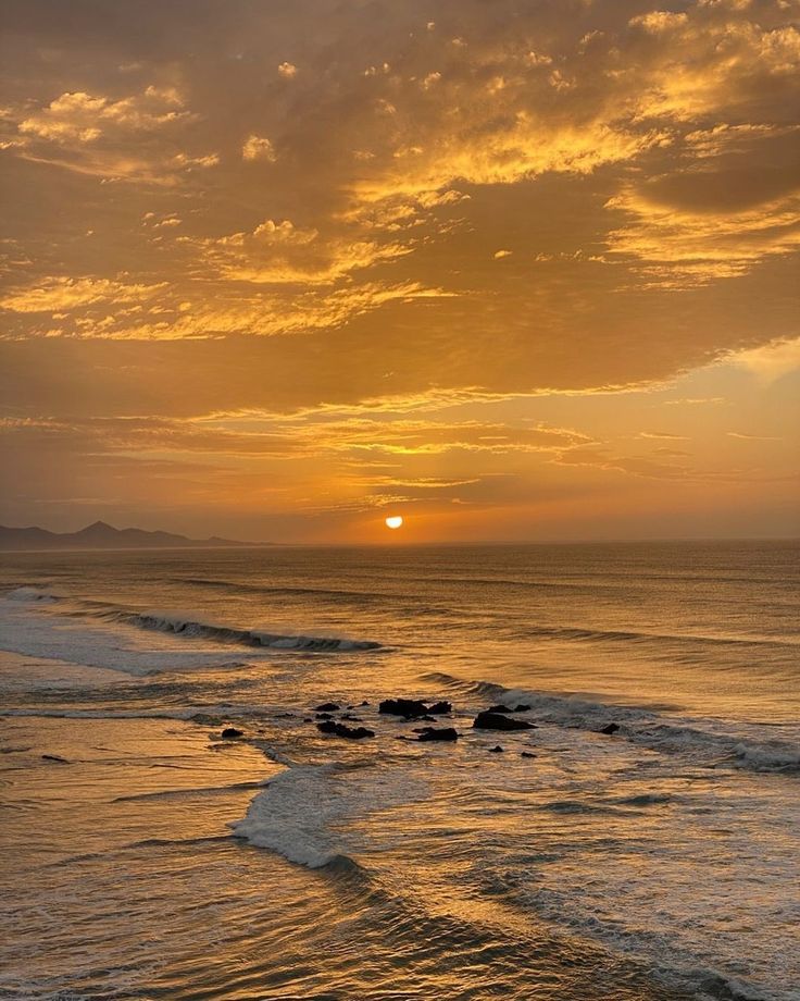 the sun is setting over the ocean with waves