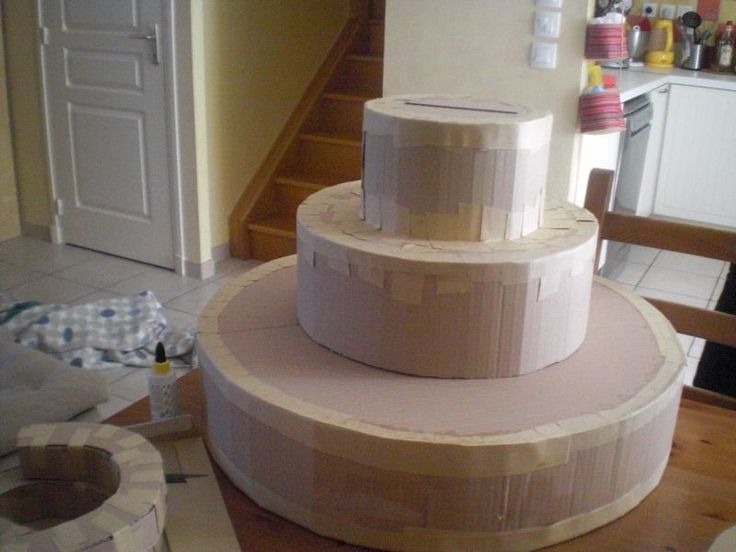 a three tiered cake sitting on top of a wooden table next to a stair case