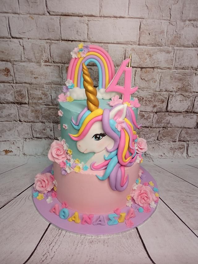 a birthday cake decorated with an unicorn's head and flowers