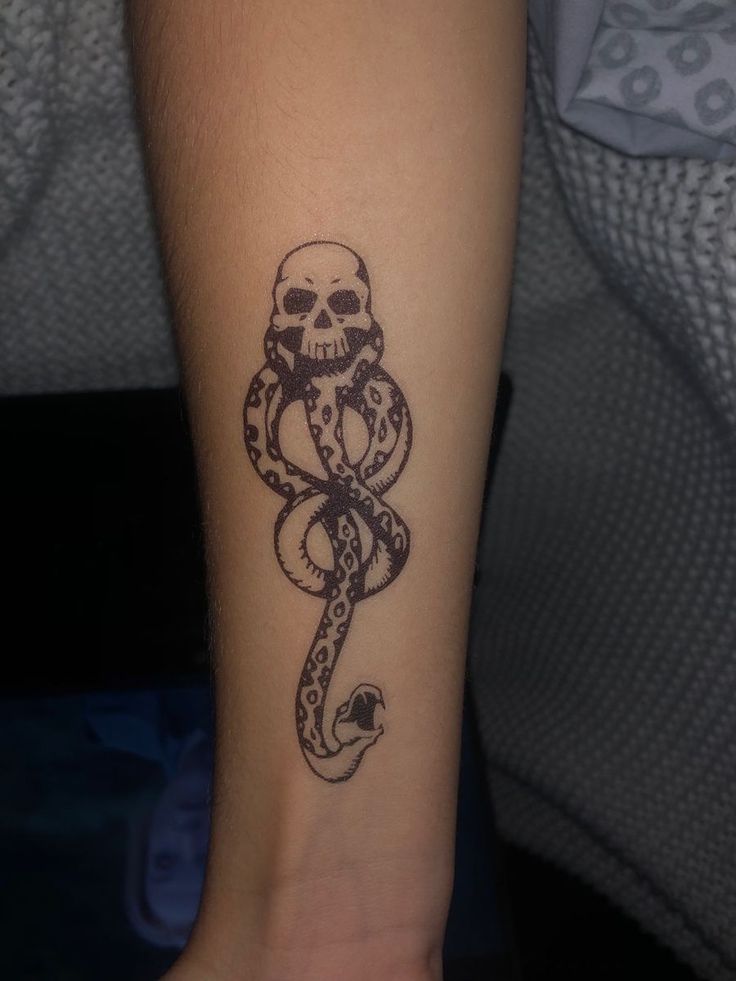 a person with a tattoo on their arm that has a snake and skull on it